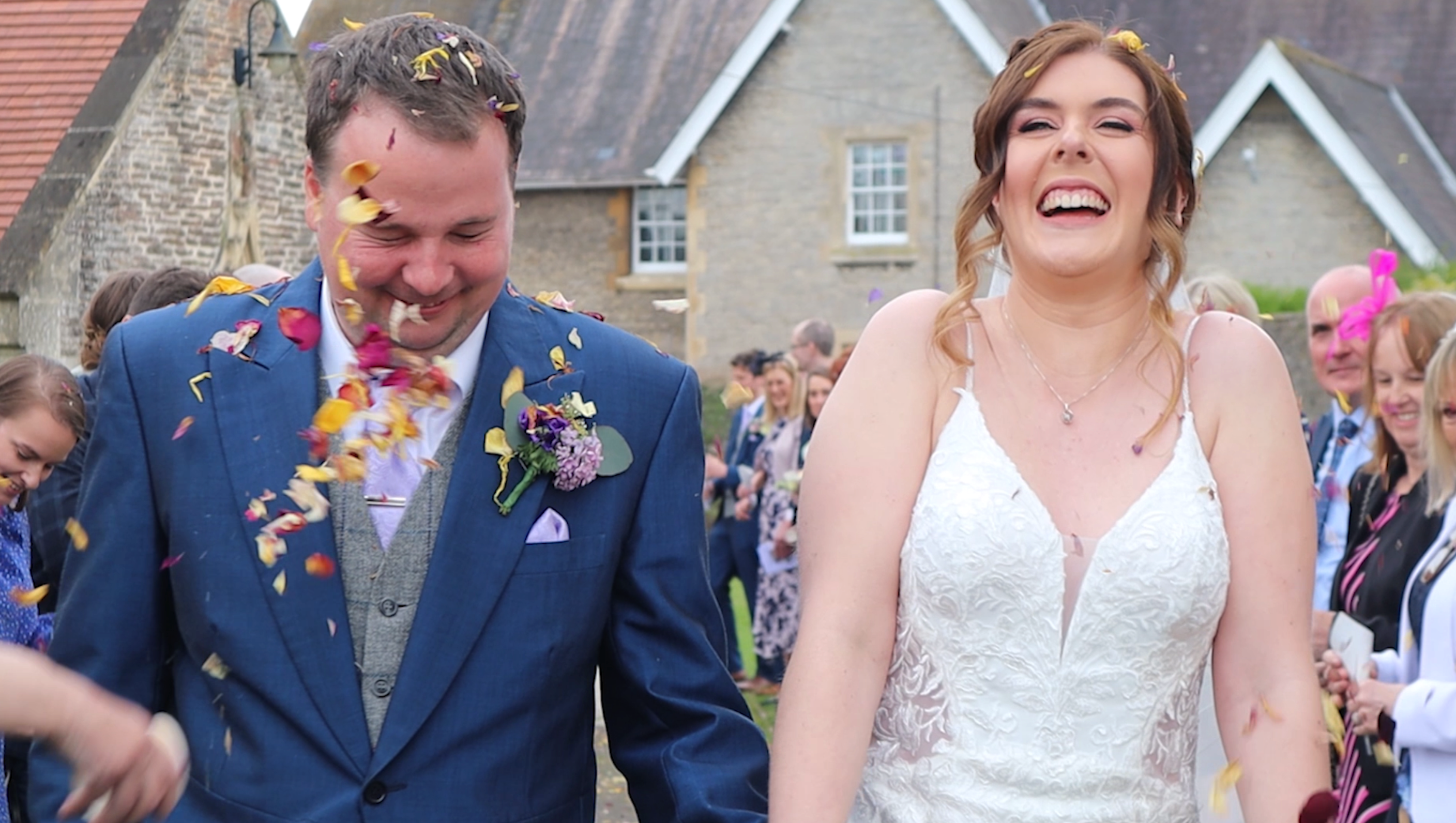 Close up of Husband and Bride walking away from wedding venue laughing having confetti thrown on them